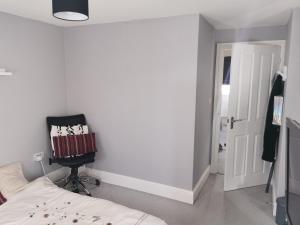 ein Schlafzimmer mit einem Bett und einem schwarzen Stuhl in der Unterkunft The Grange Cute Modern Stay in Gerrards Cross