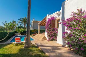 a house with purple flowers next to a swimming pool at Villa Pastor in Cala Anguila