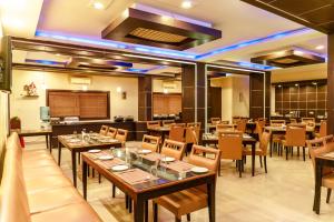 a restaurant with tables and chairs in a room at Bisque Magaji Orchid - Malleshwaram, Near Mantri Square Mall & Majestic in Bangalore