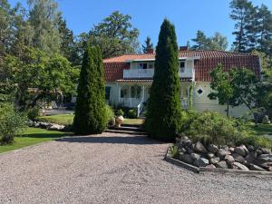 a house with two trees and a gravel driveway at Fridfull idyll intill sjö in Uppsala