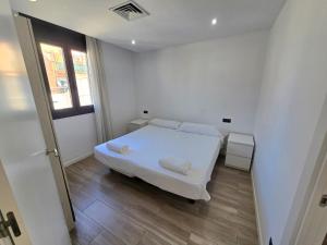 a white bedroom with a bed and a window at SM Apartments Station in Lleida