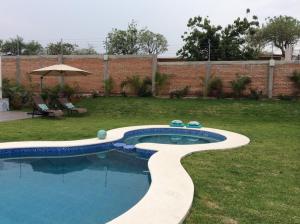 a swimming pool in a yard with an umbrella at Casa El Camino in Amatlán