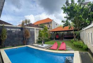 a pool with two red pillows next to a house at The Surya Kuta Villa in Kuta
