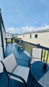 a deck with two chairs and a table on a balcony at Pure Living -West Sands, Quiet Grassy retreat Seal Bay in Selsey