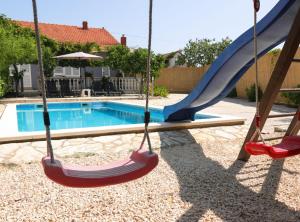a swing set in front of a swimming pool at Holiday Home Krnić in Šibenik