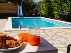 a table with two glasses of orange juice and a plate of bread at Holiday Home Krnić in Šibenik