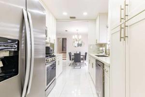 a white kitchen with a refrigerator and a dining room at Stylish 3BR Home - BBQ & Near Top Attractions in Miami Gardens