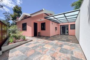 a pink house with awning and a patio at Casa Requinte - Jacuzzi in Arco da Calheta