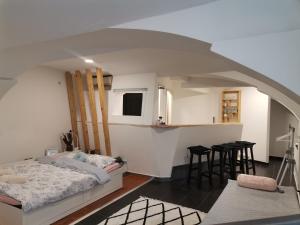 a bedroom with a bed and a kitchen with stools at F16Studió Apartman in Pécs