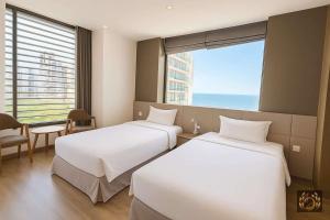 due letti in una stanza d'albergo con finestra di Kim Thanh Boutique Hotel Nha Trang a Nha Trang