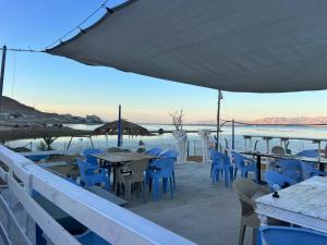 a restaurant with blue chairs and tables and water at Lord of the Dead Sea Crown Group Collection in Neve Zohar