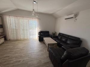 a living room with black leather furniture and a table at Cozy Apartment Kuti in Herceg-Novi