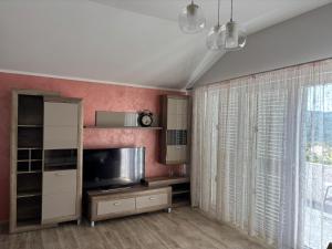 a living room with a tv and a large window at Cozy Apartment Kuti in Herceg-Novi