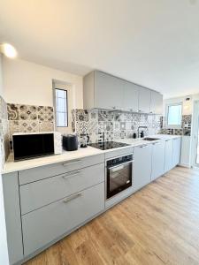 cocina grande con armarios y electrodomésticos blancos en 10m du sable Déco soignée & bâtiment de caractère, en Saint-Pierre-Quiberon