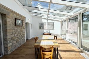 Un invernadero con una mesa larga en una habitación con ventanas. en 10m du sable Déco soignée & bâtiment de caractère, en Saint-Pierre-Quiberon