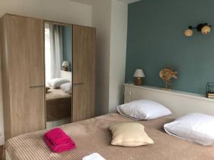 een slaapkamer met een bed met 2 kussens en een spiegel bij L'estacade avec sur mer in Le Tréport