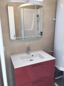 een badkamer met een rode en witte wastafel en een spiegel bij L'estacade avec sur mer in Le Tréport