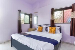a bedroom with a bed with yellow and blue pillows at Hotel O Muskaan Cottage in Matheran