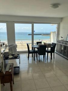 een woonkamer met een tafel en uitzicht op het strand bij Apartment facing the large beach in Quiberon