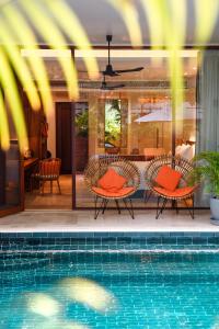 a swimming pool with orange chairs and a house at FCC Angkor by Avani in Siem Reap