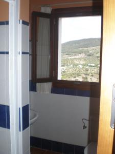 łazienka z toaletą, oknem i umywalką w obiekcie Apartamentos Rurales El Cañuelo de Carcabuey w mieście Carcabuey