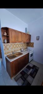 cocina con armarios de madera, fregadero y fogones en The house by the sea, en Skála Foúrkas