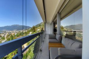 a balcony with couches and a view of a city at Chiar di Luna by Quokka 360 - loft with view of Lake Maggiore in Minusio