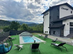 a building with a swimming pool on a green lawn at Chicago Hotel in Yaremche