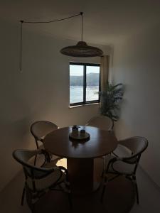 Una mesa y sillas en una habitación con ventana. en Comfort Viewpoint Sesimbra - parking at center, en Sesimbra