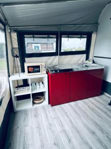 Una cocina con gabinetes rojos y un fregadero en una casa rodante. en Mietwohnwagen 49, en Hüde 2 fotos más