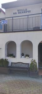 a bench in front of a white building with a balcony at Willa Na Skarpie in Krynica Morska