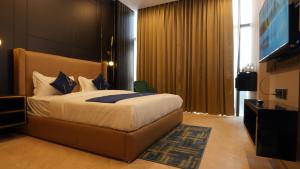 a bedroom with a large bed and a television at Aquila Grand Suites - Noida Sector 136 in Noida