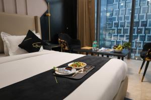 a hotel room with a bed with a tray of food on it at Aquila Grand Suites - Noida Sector 136 in Noida