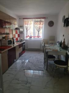 a kitchen with a table and a table and a window at Apartament Geo in Nehoiu +14 photos