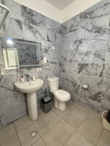 a bathroom with a white toilet and a sink at Guest House Kloen in Vlorë +7 photos