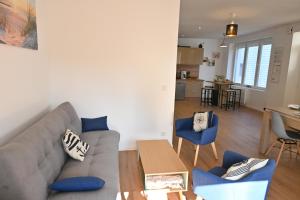 Una sala de estar con un sofá gris y sillas azules. en L'Auberge Du Roch, en Saint-Pierre-Quiberon