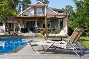 a pair of lounge chairs and a pool in front of a house at Gyra Villas - Villa Ermis with private pool in Lefkada