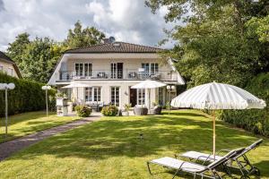汉堡Exklusive Traumvilla mit Sauna的一座房子,配有两把草坪椅和一把伞