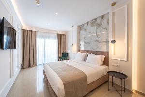 a hotel room with a large bed and a tv at Philia Center Suites in Rhodes Town