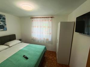a small bedroom with a bed and a television at Apartments Valter Frankovic in Mošćenička Draga