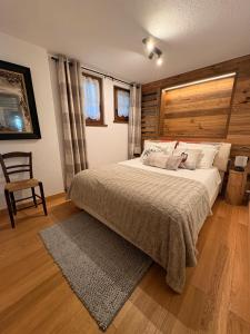 Un dormitorio con una cama grande y una silla. en L'Atelier du Temps - Maison du Glacier, en Entrèves