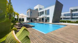 a swimming pool on a wooden deck next to a building at Cove Seaview Villas - Neptune in Ayia Napa