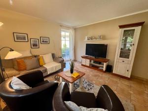 a living room with a couch and chairs and a television at Birkenhof App 67 in Wustrow