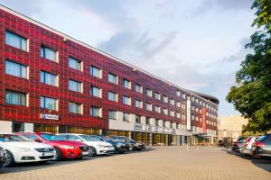 布拉格Iris Hotel Eden - Czech Leading Hotels的一座红砖建筑,前面停有汽车