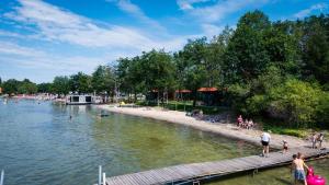 a group of people on a beach near a body of water at Houseboats Dollar - Plaża Nowe Guty in Nowe Guty