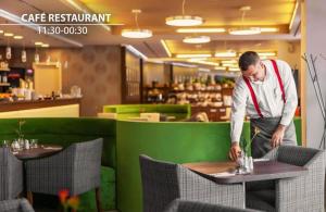 布拉格Iris Hotel Eden - Czech Leading Hotels的一名男子站在咖啡餐厅的桌边