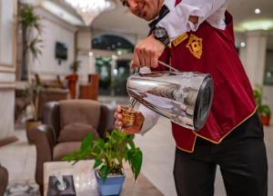 a man is pouring a drink into a pot at Taj Celine Hotel in Jeddah