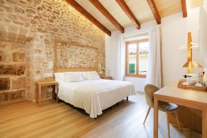 a bedroom with a bed and a stone wall at Petit Palau Alcudia - Adults Only in Alcudia