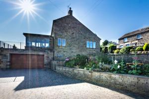 a stone house with a brick wall and a garage at Feathered Nest in Hornby