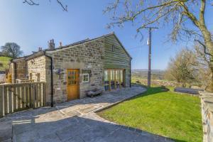 a stone cottage with a wooden door and a yard at Hardwick House Barn in Addingham
